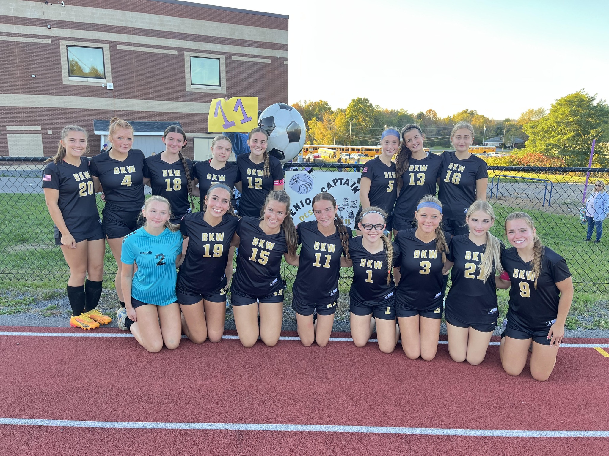girls soccer team standing on track posing for photo