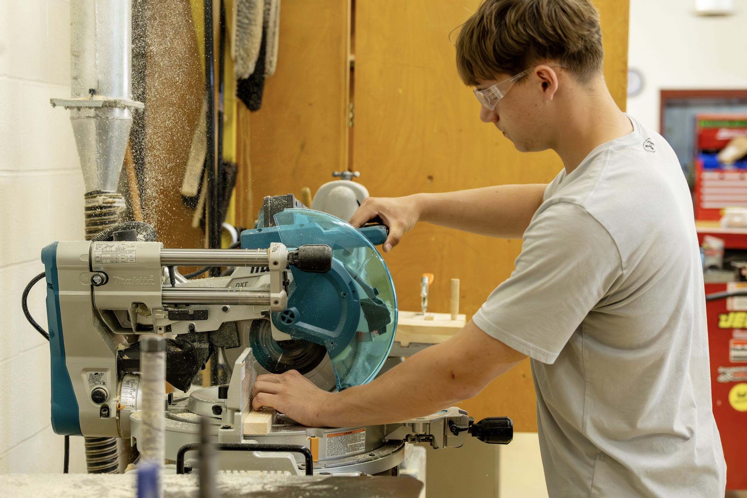 A high school student uses and electric saw