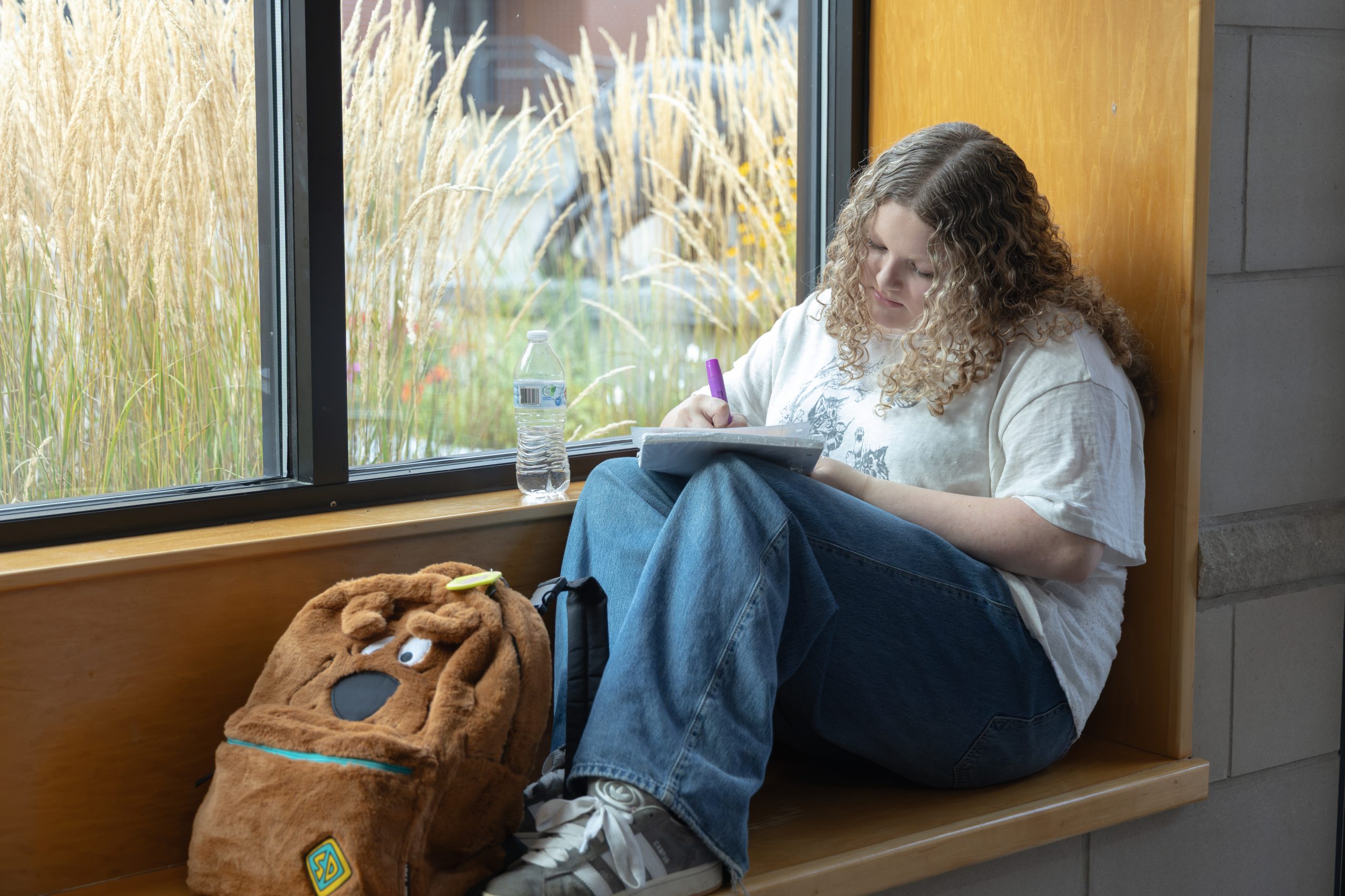 Secondary student sitting on a bench writing on a notebook