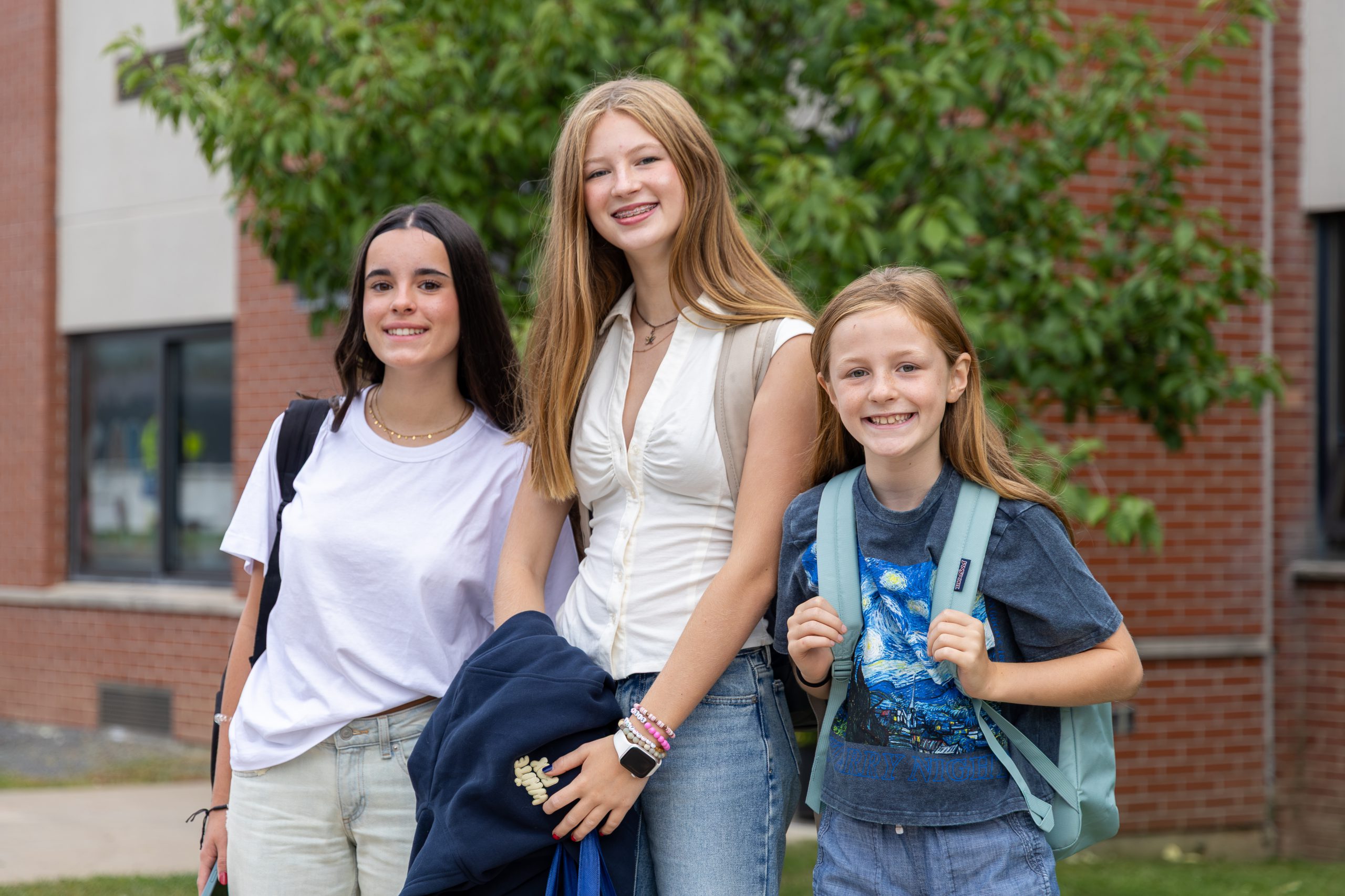 Three secondary students smiling outside