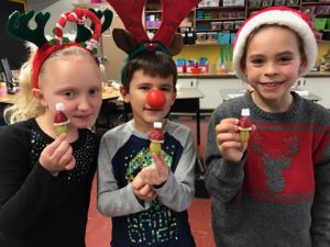three elementary students holding their hearts for act of kindness.