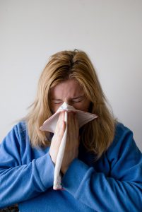 A woman blows her nose into a tissue