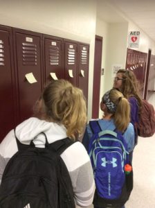 students reading sticky notes on a locker