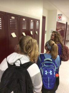 students reading sticky notes on a locker