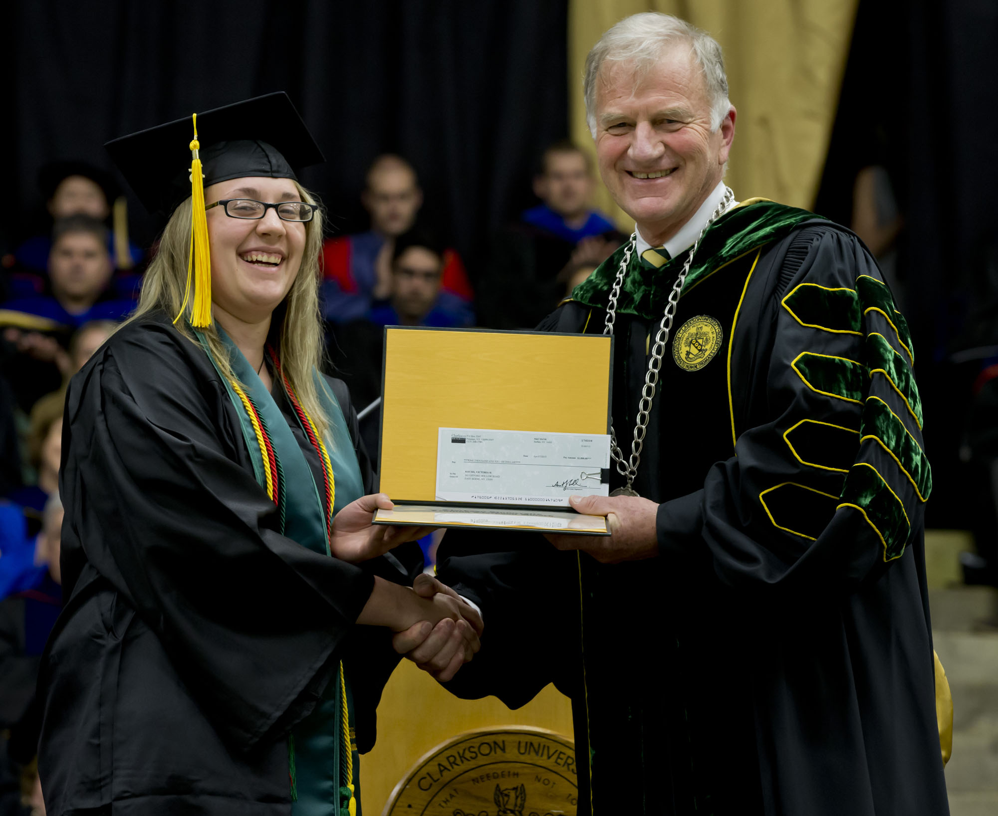 college graduate is presented an award in cap and gown