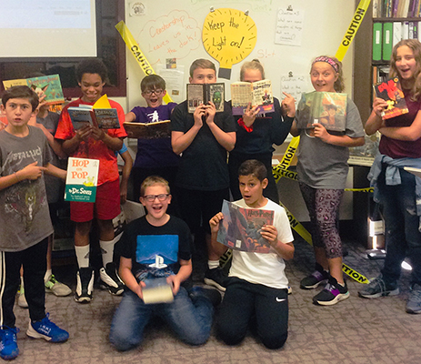 boys and girls in a group in library holding books