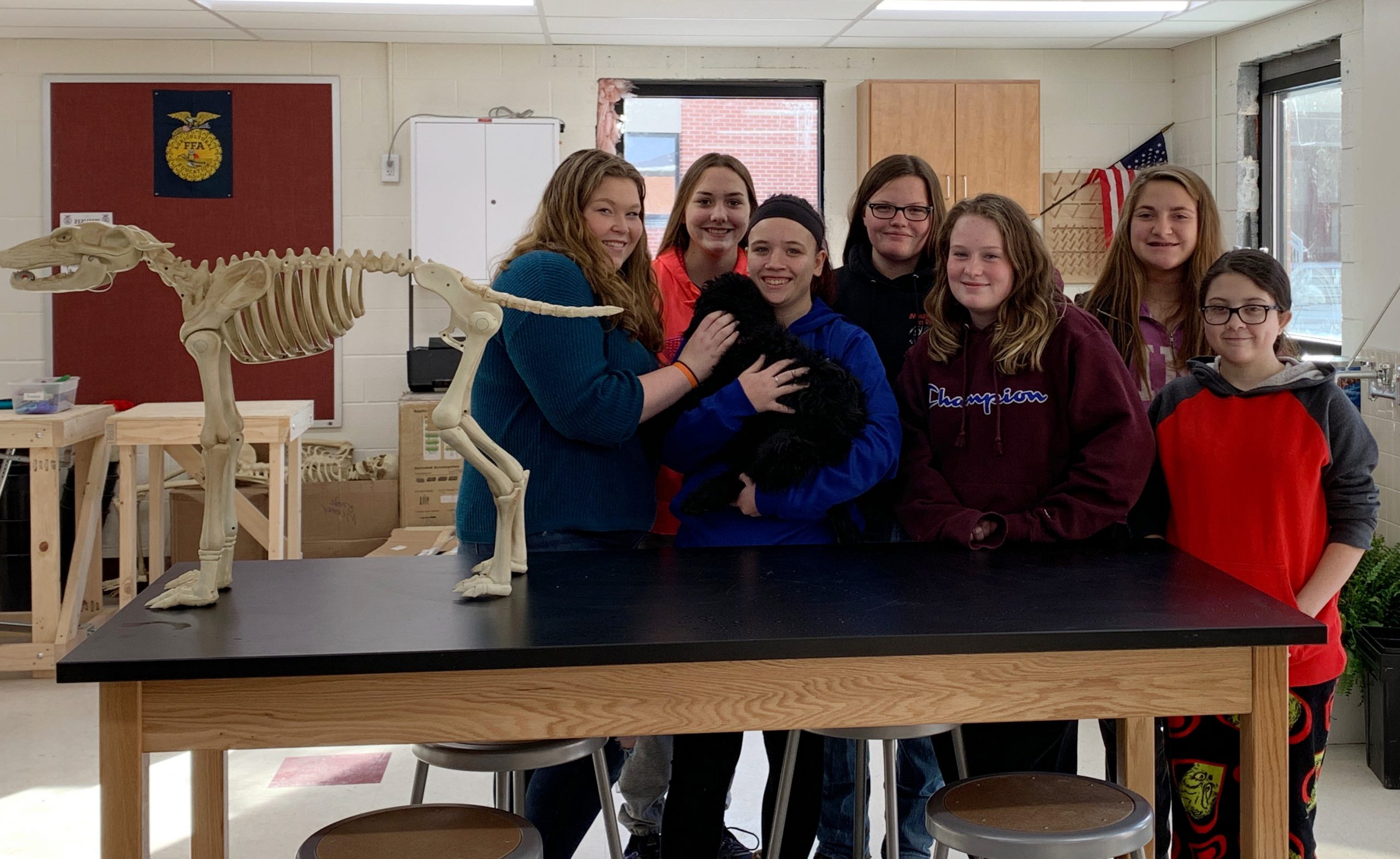 group of student hold a black dog