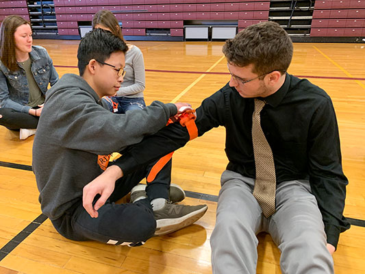 a student applies a tourniquet to another student