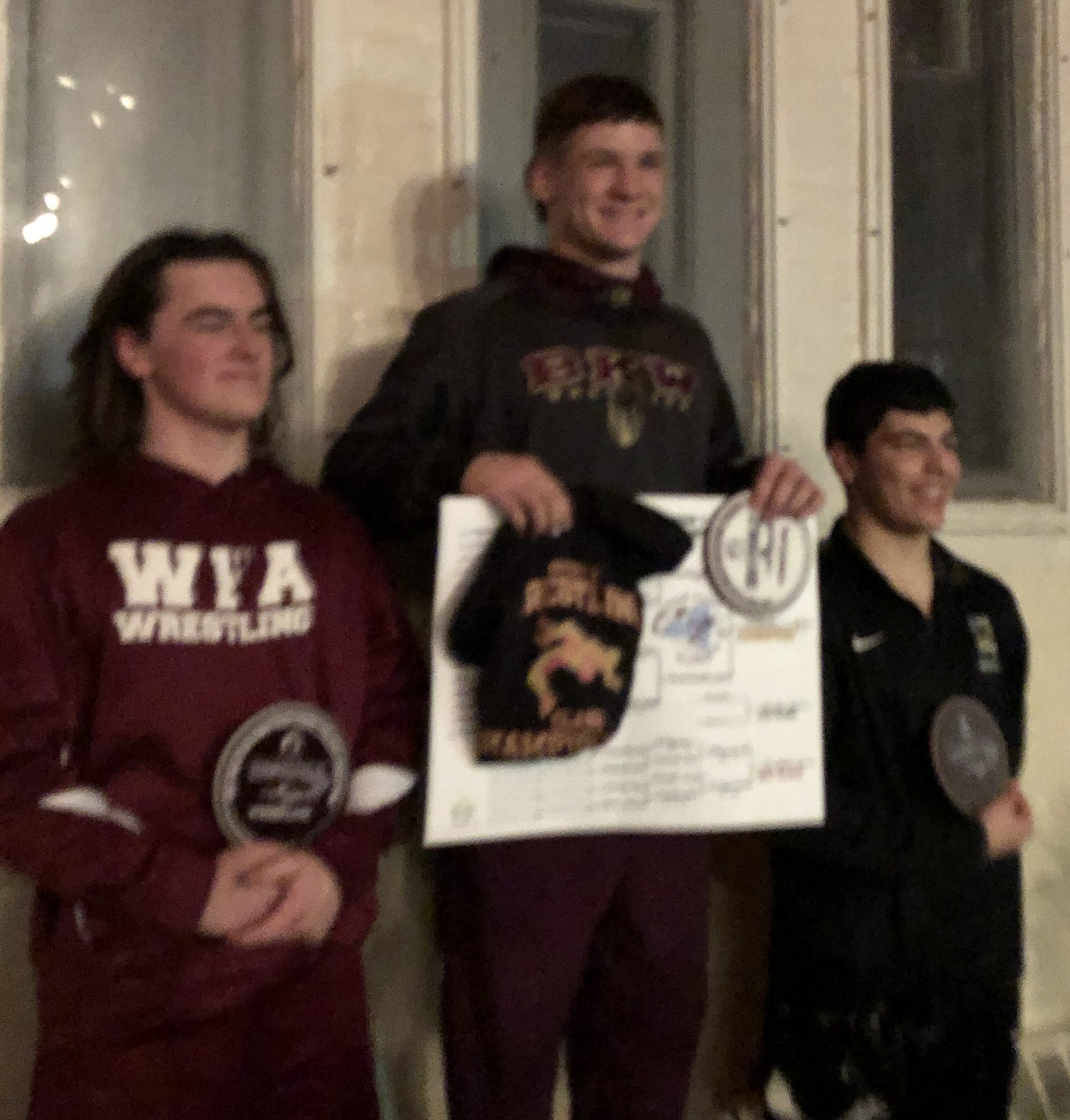 three boy wrestlers the middle one holding a white sign