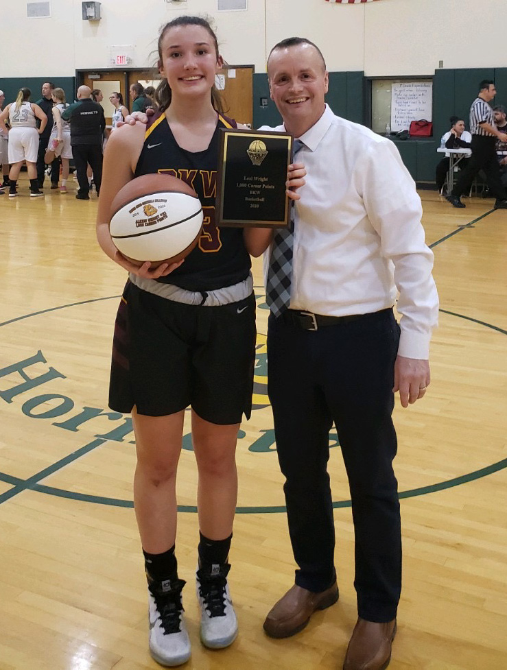 girl stands next to coach holding a basketball