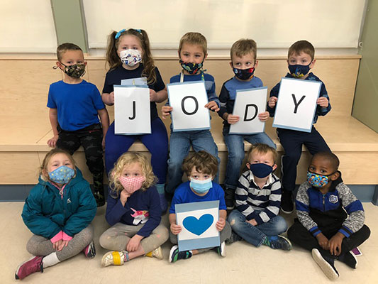 students wearing blue and holding cards that spell out Jody