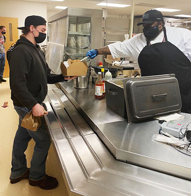 student is served food by Mr. Clark