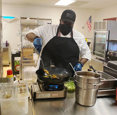 Mr. Clark stirring food in a wok