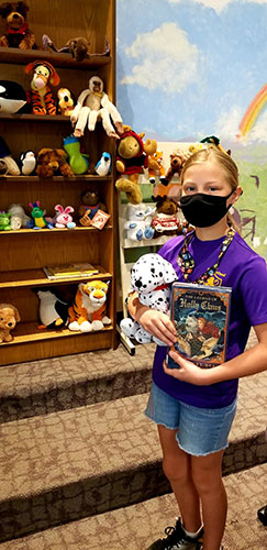 student holding library book and stuffed animal