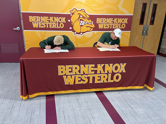 Zeke and Quinn signing letters at table