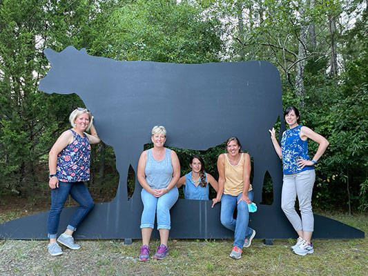 Teachers standing in front of metal cow