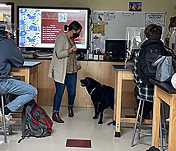 Dr. Emmerich with Maggie in front of the class in the classroom