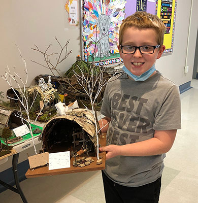 student holding their longhouse project