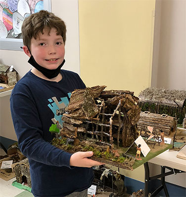 student holding their longhouse project