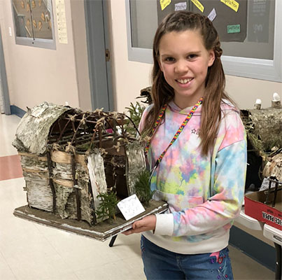 student holding their longhouse project