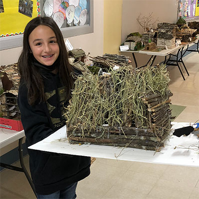 student holding their longhouse project