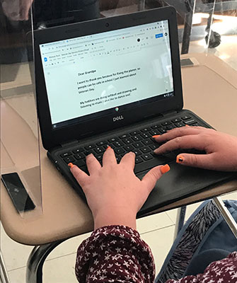 student's hands on keyboard writing thank you letter to their veteran and grandfather