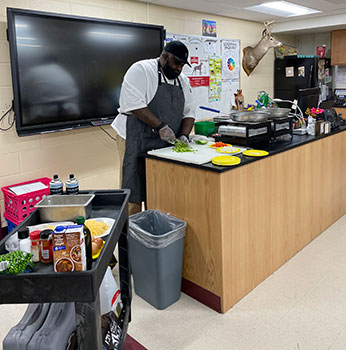 Lateef Clark cutting food in classroom