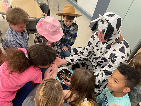 student dressed as cow talking to younger students