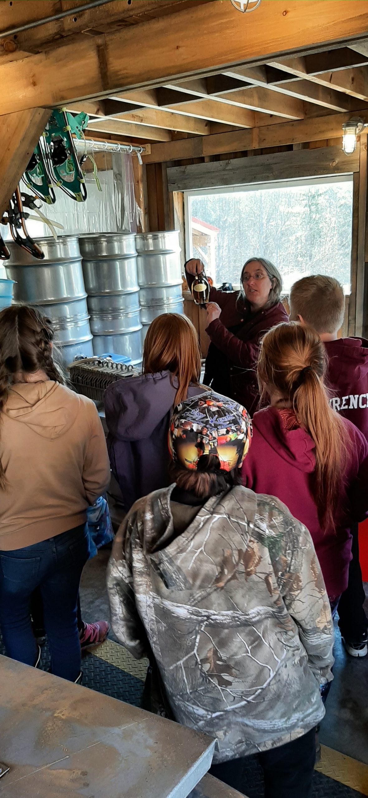 student watch a woman harvest maple sap