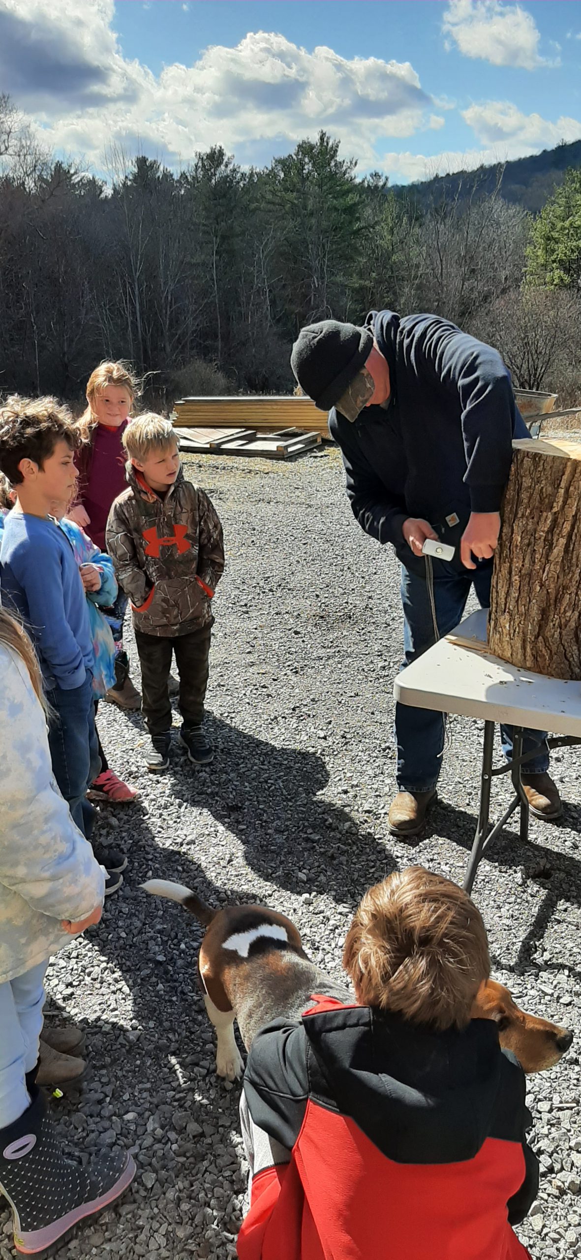 student watch a man chisel a log