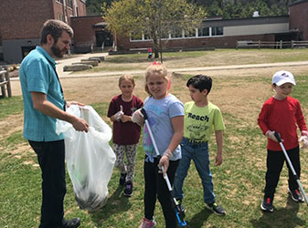 teacher holding back, students picking up trash