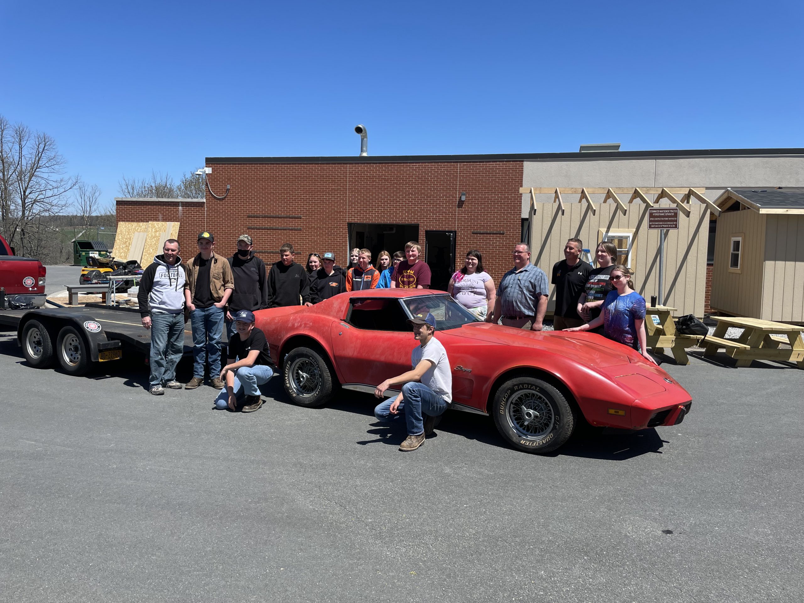 group gathers around old Corvette