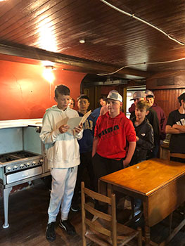 students in kitchen, 1 holding a folder