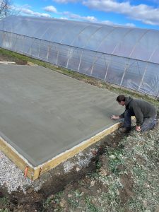 BKW senior Aaron Carr putting the final touches on the concrete foundation for the outdoor classroom space on the BKW campus.