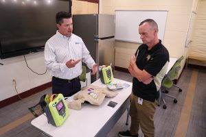 Zoll Medical Senior Channel Partner Manager and BKW parent Matthew Monroe highlights the procedures of the AED to BKW Athletic Director Mr. Gavin.