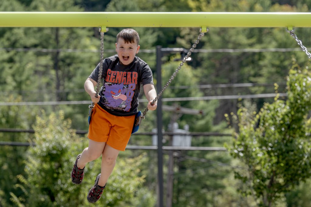 young student smiling having fun on swingset