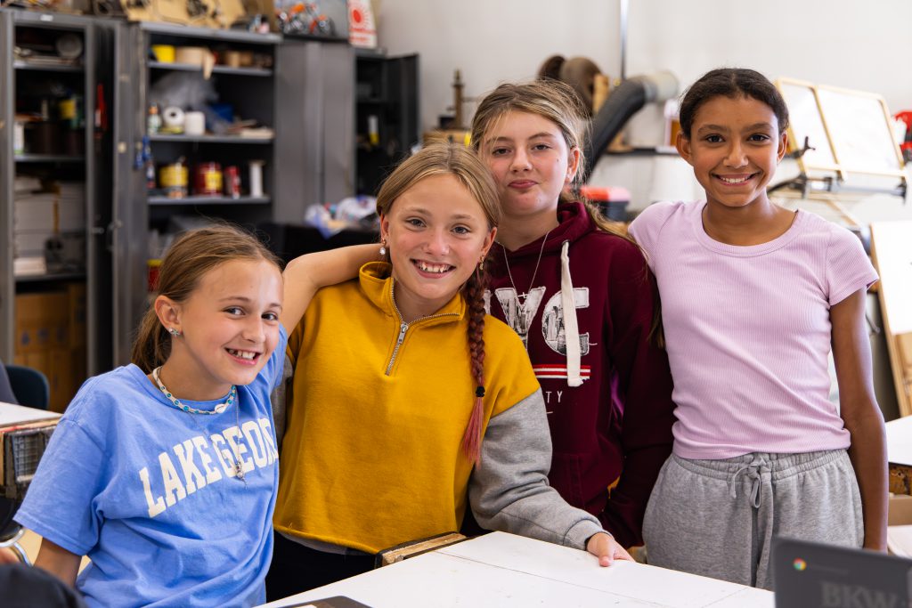 four young students smiling and posing for the camera