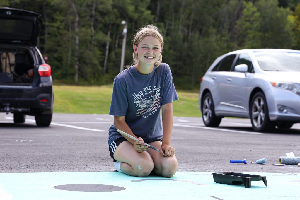 student smiling and painting parking lot