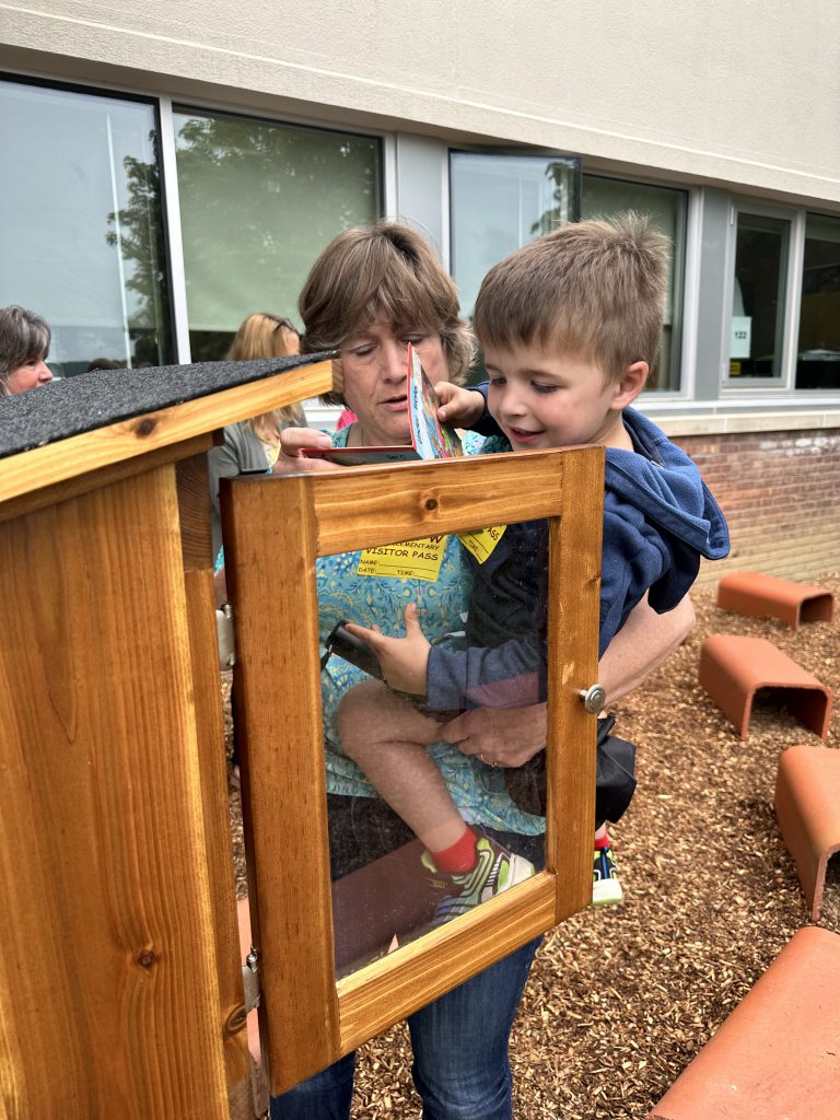 teacher and young student viewing the outdoor library