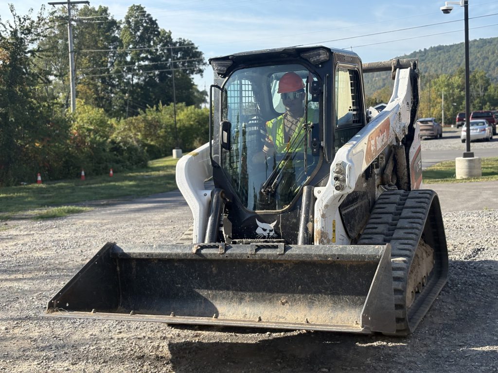 student wearing workplace safety gear drives a bulldozer