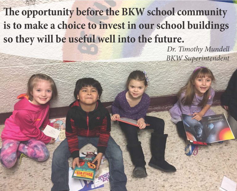 four young students looking up and smiling with books in their hands