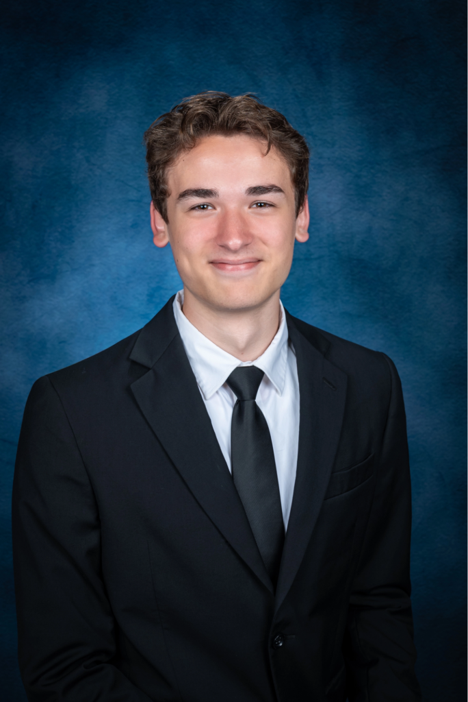Smiling teen with dark hair wearing a suit and neck tie.