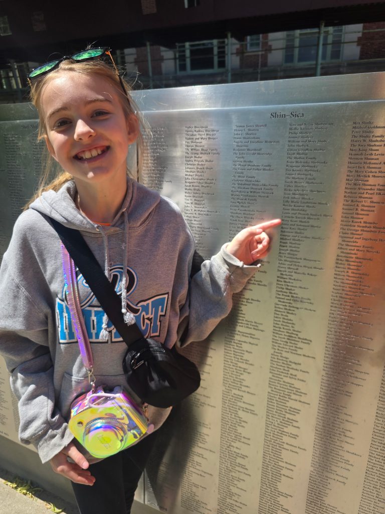 Student pointing to an ancestor's name on the American Immigrant Wall of Honor