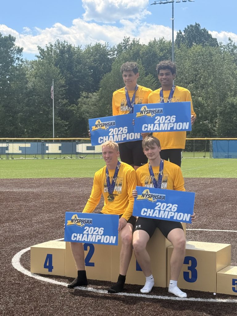 Four BKW track runners at the podium holding 2026 champion signs
