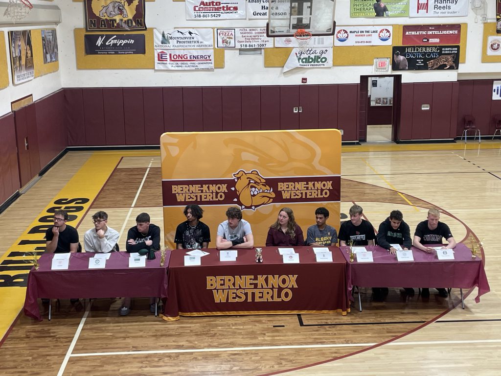 Eleven students signing college athletics letters of intent in a gym