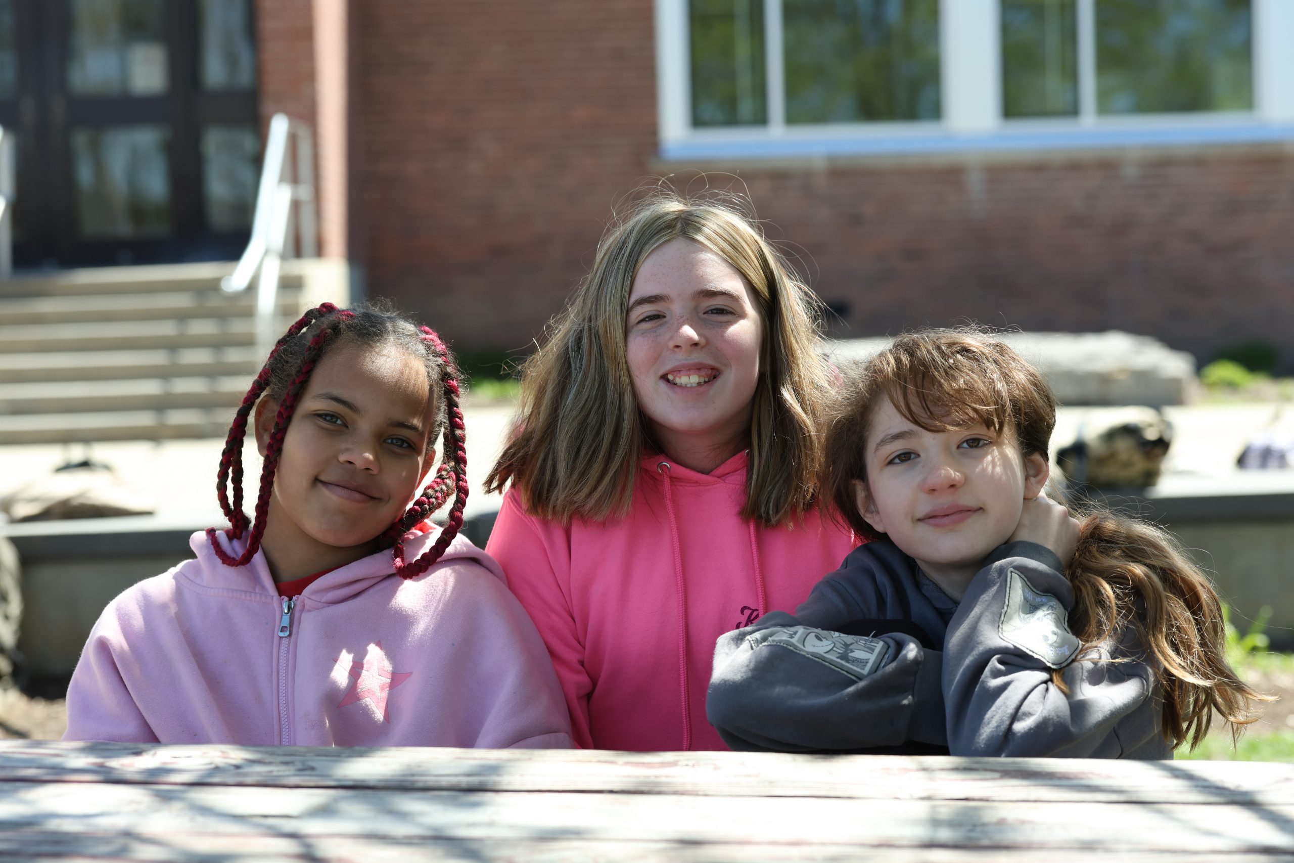 Three students outside a brick school smiling