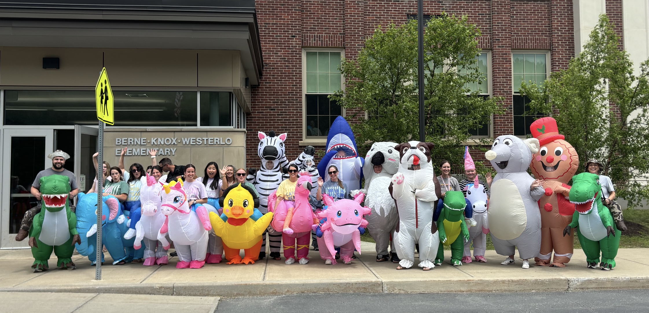 Employees dressed in blow up costumes standing outside BKW Elementary School