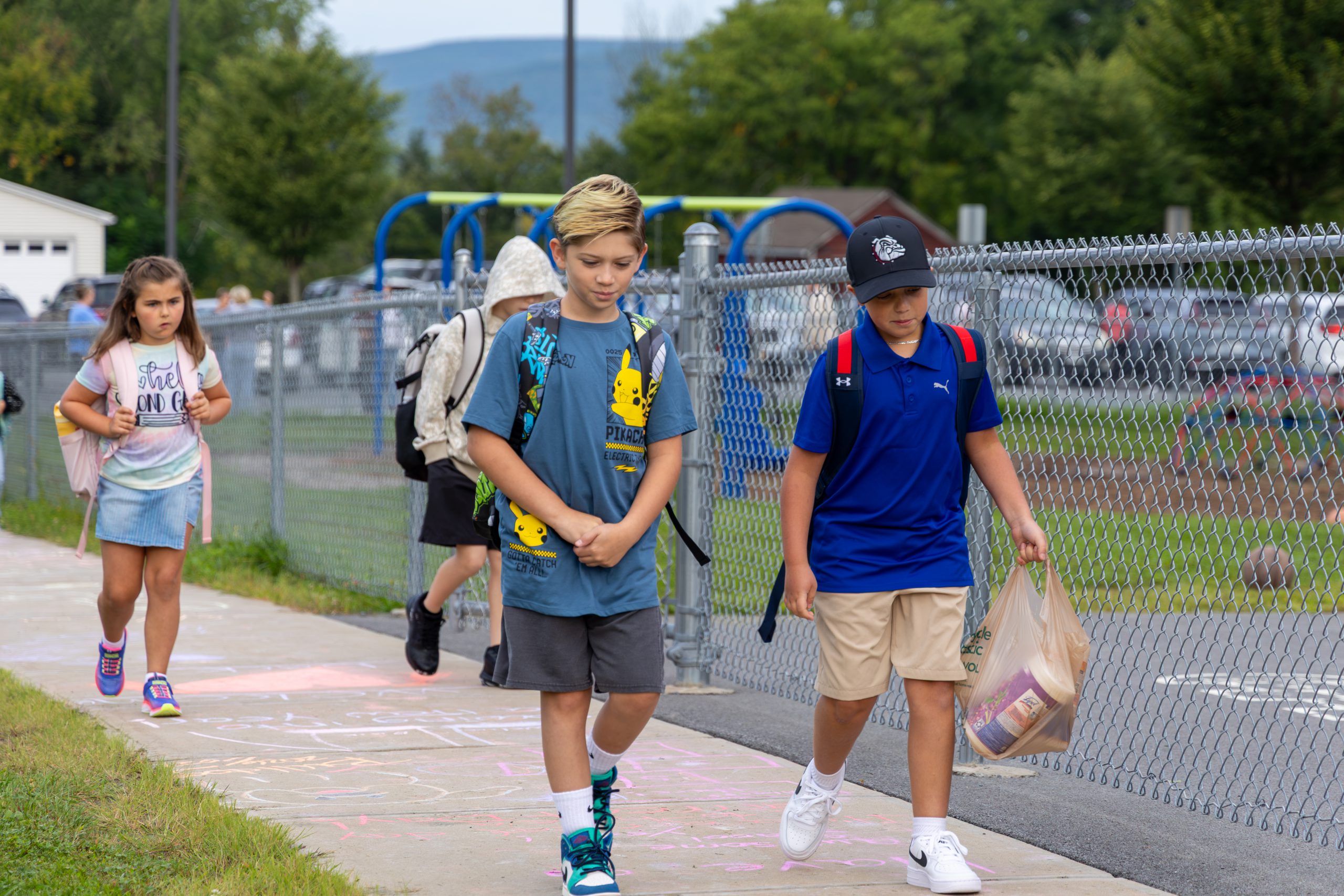 Four elementary students walking on the sidewalk